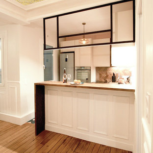 Contemporary u-shaped eat-in kitchen in Paris with an integrated sink, beaded inset cabinets, beige cabinets, wood benchtops, timber splashback, panelled appliances, cement tiles, with island and blue floor.