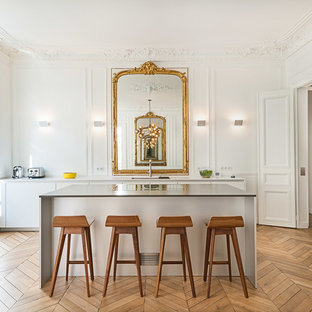 Inspiration pour une grand cuisine ouverte parallèle traditionnelle avec des portes de placard blanches, un sol en bois clair, un placard à porte plane, un îlot central, une crédence blanche et une crédence en bois.