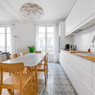 Aménagement d'une grand cuisine ouverte linéaire scandinave avec un évier posé, des portes de placard blanches, un plan de travail en bois, une crédence blanche, une crédence en dalle métallique, un sol en carreaux de ciment, aucun îlot, un placard à porte plane, un sol gris et un plan de travail marron.