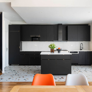 Inspiration pour une cuisine ouverte linéaire design de taille moyenne avec un placard à porte plane, des portes de placard noires, une crédence blanche, un électroménager encastrable, un îlot central, un sol multicolore et un plan de travail blanc.