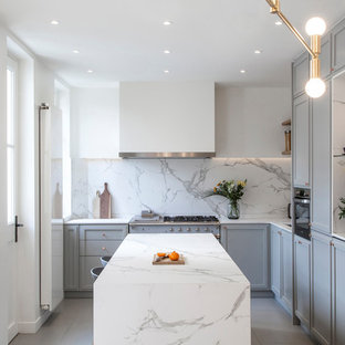 Idée de décoration pour une cuisine design en L avec un placard avec porte à panneau encastré, des portes de placard grises, une crédence blanche, une crédence en dalle de pierre, un îlot central, un sol gris et un plan de travail blanc.