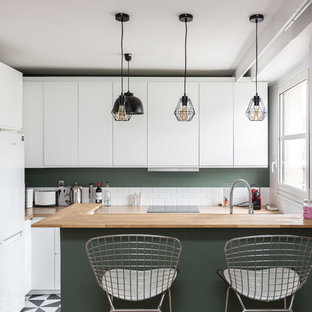 Inspiration pour une cuisine nordique en L fermée avec un placard à porte plane, des portes de placard blanches, un plan de travail en bois, une crédence blanche, une crédence en carrelage métro, un électroménager blanc, une péninsule et un sol noir.