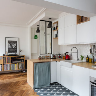 Small scandinavian l-shaped eat-in kitchen in Paris with a farmhouse sink, flat-panel cabinets, white cabinets, wood benchtops, white splashback, ceramic splashback, stainless steel appliances, cement tiles, no island, grey floor and beige benchtop.