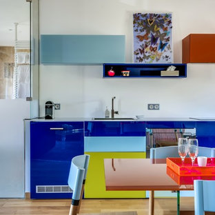 Aménagement d'une cuisine américaine linéaire contemporaine de taille moyenne avec un placard à porte plane, un sol en bois clair, des portes de placard bleues et aucun îlot.