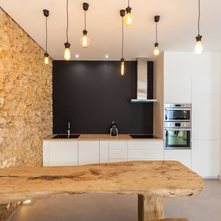 Exemple d'une cuisine ouverte linéaire montagne avec un placard à porte plane, des portes de placard blanches, un plan de travail en bois, une crédence noire, un électroménager en acier inoxydable, béton au sol, aucun îlot et un sol gris.