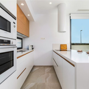 Imagen de cocina de galera, contemporánea, de tamaño medio, con fregadero de un seno, armarios con paneles lisos, puertas de armario blancas, salpicadero de vidrio, península, suelo beige y encimeras blancas