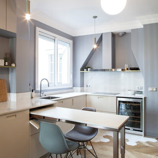 Réalisation d'une cuisine américaine design en L avec un évier encastré, un placard à porte plane, des portes de placard beiges, un électroménager en acier inoxydable, un sol en bois brun, une péninsule, un sol marron et un plan de travail blanc.