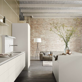 Imagen de cocina de galera, contemporánea, de tamaño medio, abierta, con fregadero bajoencimera, puertas de armario blancas, electrodomésticos con paneles y una isla