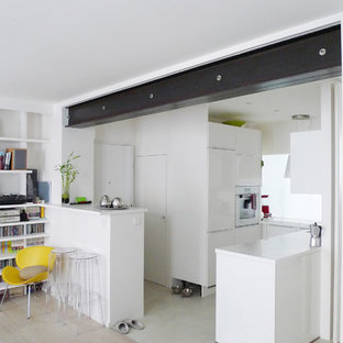 Cette image montre une cuisine ouverte design en L de taille moyenne avec des portes de placard blanches, un sol en bois clair et une péninsule.
