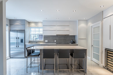 This is an example of a large modern galley open plan kitchen in Montreal with a submerged sink, grey cabinets, quartz worktops, grey splashback, ceramic splashback, stainless steel appliances, ceramic flooring and an island.