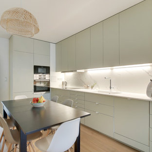 Aménagement d'une cuisine américaine scandinave avec un évier 1 bac, un placard à porte plane, des portes de placard grises, une crédence blanche, une crédence en marbre, un sol en bois clair, un sol beige et un plan de travail blanc.