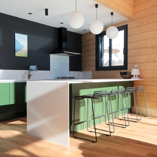 Idée de décoration pour une cuisine ouverte parallèle chalet de taille moyenne avec un placard à porte plane, des portes de placards vertess, un plan de travail en surface solide, une crédence blanche, un sol en bois clair, un plan de travail blanc, une crédence en feuille de verre et une péninsule.