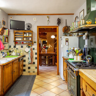 Inspiration pour une cuisine parallèle rustique avec un évier 2 bacs, un placard avec porte à panneau encastré, des portes de placard en bois brun, une crédence beige, un électroménager de couleur, un sol beige et un plan de travail beige.