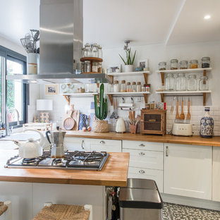 Inspiration pour une cuisine bohème en U avec un évier de ferme, un placard à porte shaker, des portes de placard blanches, un plan de travail en bois, une crédence blanche, une crédence en carrelage métro, un électroménager en acier inoxydable, une péninsule et un sol gris.