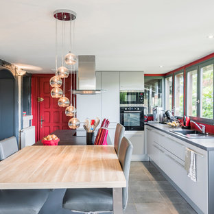 Réalisation d'une cuisine bohème avec une crédence en fenêtre, un électroménager noir et un sol gris.
