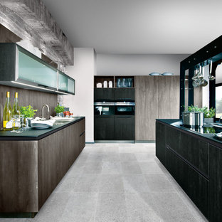 Cette image montre une très grand cuisine ouverte linéaire traditionnelle avec un îlot central, un placard à porte plane, des portes de placard en bois brun, une crédence marron, une crédence en bois, un électroménager noir et un sol gris.