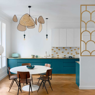Réalisation d'une cuisine américaine nordique avec un évier 1 bac, un placard à porte plane, des portes de placard turquoises, une crédence multicolore et un sol en bois brun.