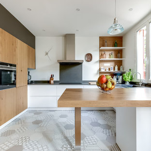 Aménagement d'une cuisine américaine contemporaine en U avec un évier encastré, un placard à porte plane, des portes de placard en bois brun, un plan de travail en bois, une péninsule et une crédence blanche.