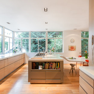 Idées déco pour une cuisine parallèle contemporaine fermée et de taille moyenne avec un placard à porte plane, un îlot central, un évier 2 bacs, des portes de placard en bois clair et un sol en bois clair.