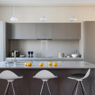 Inspiration pour une petit cuisine américaine parallèle design avec un évier encastré, un placard à porte plane, des portes de placard grises, une crédence grise, un sol en bois foncé, un îlot central et un plan de travail en inox.