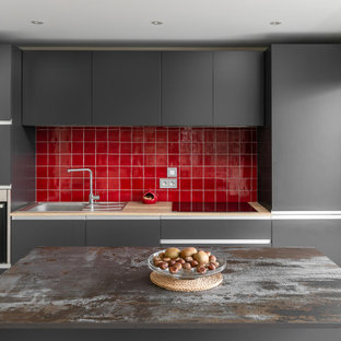 Idée de décoration pour une petit cuisine ouverte parallèle design avec un évier posé, un placard à porte affleurante, des portes de placard grises, un plan de travail en surface solide, une crédence rouge, une crédence en carreau de céramique, un électroménager en acier inoxydable, béton au sol, un îlot central et un plan de travail jaune.