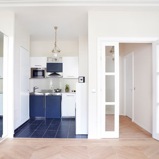 Idées déco pour une petit cuisine ouverte linéaire contemporaine avec un placard à porte plane, des portes de placard blanches, un sol en bois clair et aucun îlot.