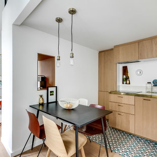 Réalisation d'une cuisine américaine linéaire design de taille moyenne avec un évier posé, un placard à porte plane, des portes de placard en bois clair, un plan de travail en inox, un sol en bois clair, aucun îlot, une crédence blanche et un électroménager encastrable.