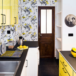Idée de décoration pour une cuisine parallèle bohème avec un évier posé, un placard à porte plane, des portes de placard jaunes, un sol noir et un plan de travail noir.