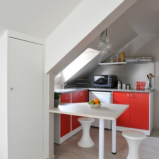 Inspiration pour une petit cuisine américaine design en L avec un placard à porte plane, des portes de placard rouges, un sol en bois clair et une péninsule.