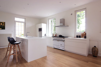 Medium sized eclectic single-wall enclosed kitchen in Marseille with a single-bowl sink, beaded cabinets, white cabinets, white splashback, white appliances, light hardwood flooring, an island, beige floors, white worktops and laminate countertops.