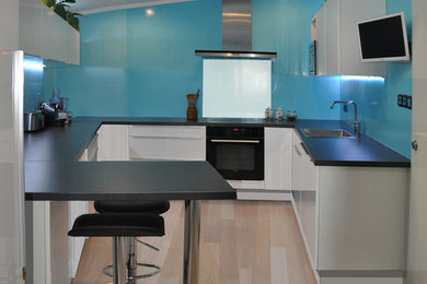 Imagen de cocinas en U contemporáneo de tamaño medio cerrado con armarios con rebordes decorativos, puertas de armario blancas, encimera de cuarzo compacto y salpicadero azul