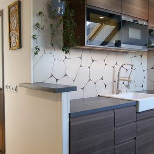 Exemple d'une cuisine linéaire tendance avec un évier de ferme, un placard à porte plane, des portes de placard en bois sombre, une crédence jaune, un électroménager noir, un sol gris et un plan de travail gris.