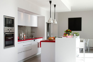 Idéer för ett mellanstort modernt röd linjärt kök med öppen planlösning, med en undermonterad diskho, luckor med profilerade fronter, vita skåp, laminatbänkskiva, grått stänkskydd, rostfria vitvaror och en köksö