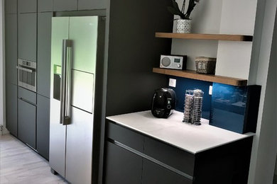 Modelo de cocina actual con encimera de acero inoxidable, salpicadero azul, electrodomésticos de acero inoxidable y encimeras blancas