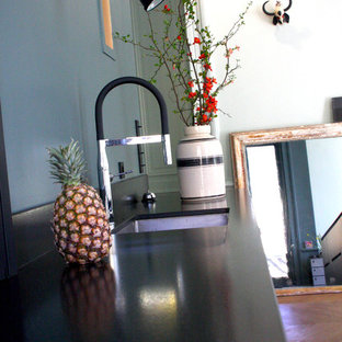 This is an example of a large modern single-wall eat-in kitchen in Lyon with an undermount sink, black splashback, marble splashback, light hardwood floors, beige floor, black benchtop, beaded inset cabinets, light wood cabinets, black appliances and with island.