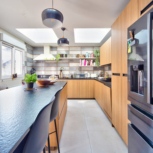 Idées déco pour une cuisine classique en L fermée avec un placard à porte plane, des portes de placard en bois brun, une crédence grise, un électroménager en acier inoxydable, un îlot central, un sol beige et un plan de travail noir.