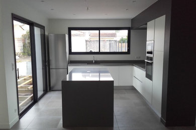 Foto på ett mellanstort funkis l-kök, med betonggolv, en köksö och grått golv