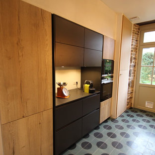 This is an example of a mid-sized industrial galley separate kitchen in Rennes with an integrated sink, flat-panel cabinets, black cabinets, granite benchtops, black splashback, black appliances, cement tiles, turquoise floor and black benchtop.