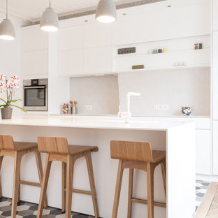 Exemple d'une cuisine tendance de taille moyenne et fermée avec un sol beige, un évier intégré, un placard à porte affleurante, des portes de placard blanches, un plan de travail en surface solide, une crédence beige, une crédence en carreau de céramique, un électroménager blanc, un sol en bois clair, un îlot central et un plan de travail blanc.