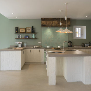 This is an example of a mid-sized country u-shaped eat-in kitchen in Other with an undermount sink, beaded inset cabinets, white cabinets, concrete benchtops, green splashback, ceramic splashback, coloured appliances, concrete floors, multiple islands, grey floor and grey benchtop.