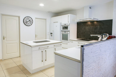 Imagen de cocina tradicional abierta con armarios con paneles lisos, salpicadero blanco, suelo de azulejos de cemento, una isla y encimeras blancas