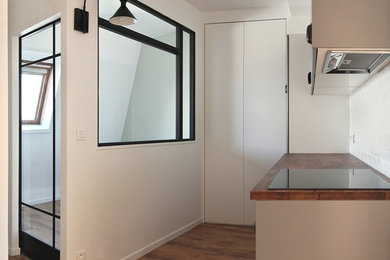 Cette image montre une petite cuisine ouverte encastrable bohème en L avec des portes de placard grises, un plan de travail en bois, une crédence blanche, sol en stratifié et aucun îlot.
