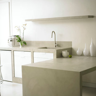 Esempio di una cucina moderna di medie dimensioni con ante bianche, top in cemento e penisola