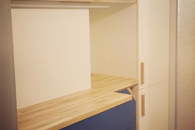 Cette photo montre une petite cuisine ouverte linéaire moderne avec un placard à porte affleurante, des portes de placard bleues et un plan de travail en bois.