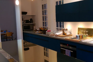 Inspiration pour une cuisine parallèle minimaliste fermée avec des portes de placard bleues, carreaux de ciment au sol et îlot.