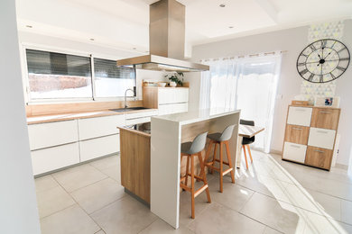 Cette image montre une cuisine américaine minimaliste en L de taille moyenne avec un placard à porte plane, un plan de travail en quartz modifié et îlot.