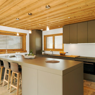 Réalisation d'une cuisine linéaire design avec un îlot central, un placard à porte plane, des portes de placards vertess, un sol en bois brun et un sol marron.