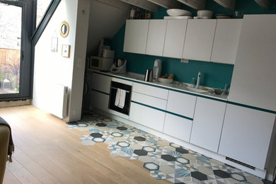 リヨンにある北欧スタイルのおしゃれなLDK (一体型シンク、白いキャビネット、珪岩カウンター、白いキッチンパネル、セメントタイルの床、アイランドなし、白いキッチンカウンター) の写真