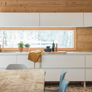 Cette photo montre une cuisine américaine linéaire tendance de taille moyenne avec un évier 2 bacs, un placard à porte plane, des portes de placard blanches, un sol multicolore, un plan de travail blanc, une crédence beige, une crédence en bois et un sol en carrelage de céramique.