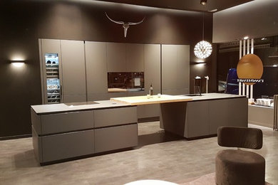 Diseño de cocina moderna grande abierta con fregadero integrado, puertas de armario grises, encimera de laminado y dos o más islas